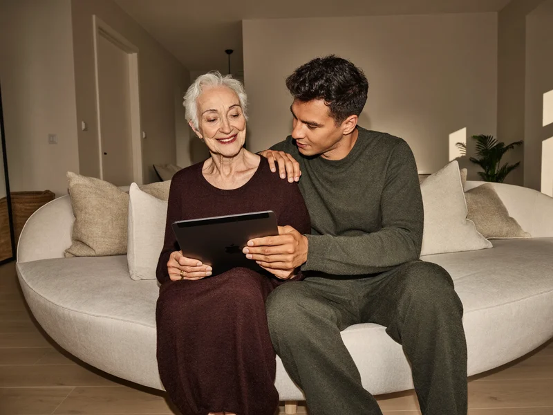 Una nonna e un nipote esplorano insieme un tablet sul divano.